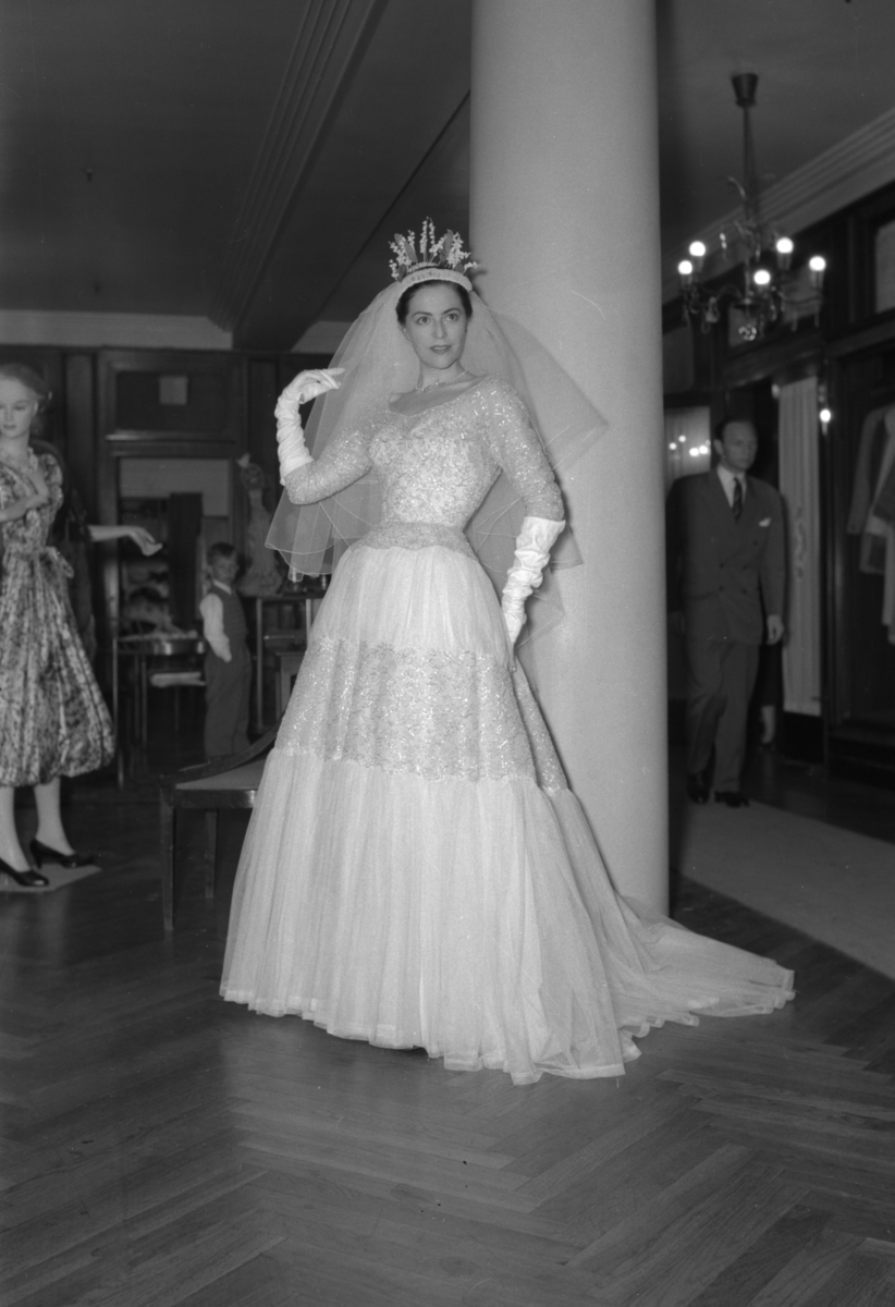 En kvinne viser fram en brudekjole. Fra en motevisning på Steen & Strøm fra 7. mai 1954..