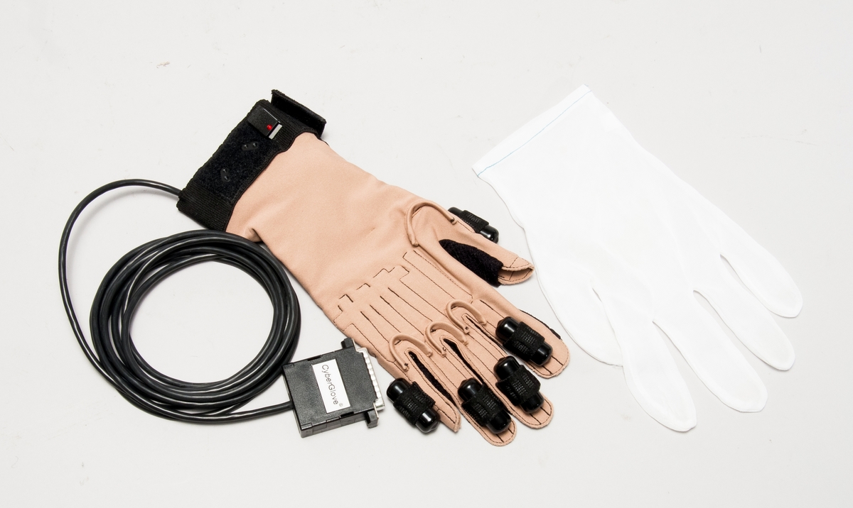 Handske (höger hand) för motion capture-utrustning, med styrenhet-VTi model nr CGIU2402, sernr 1506, för anslutning till kontrollenhet. Med stötskyddande plastask för förvaring samt nätaggregat-EL PAC power systems model CMI 1231 sernr 002992.