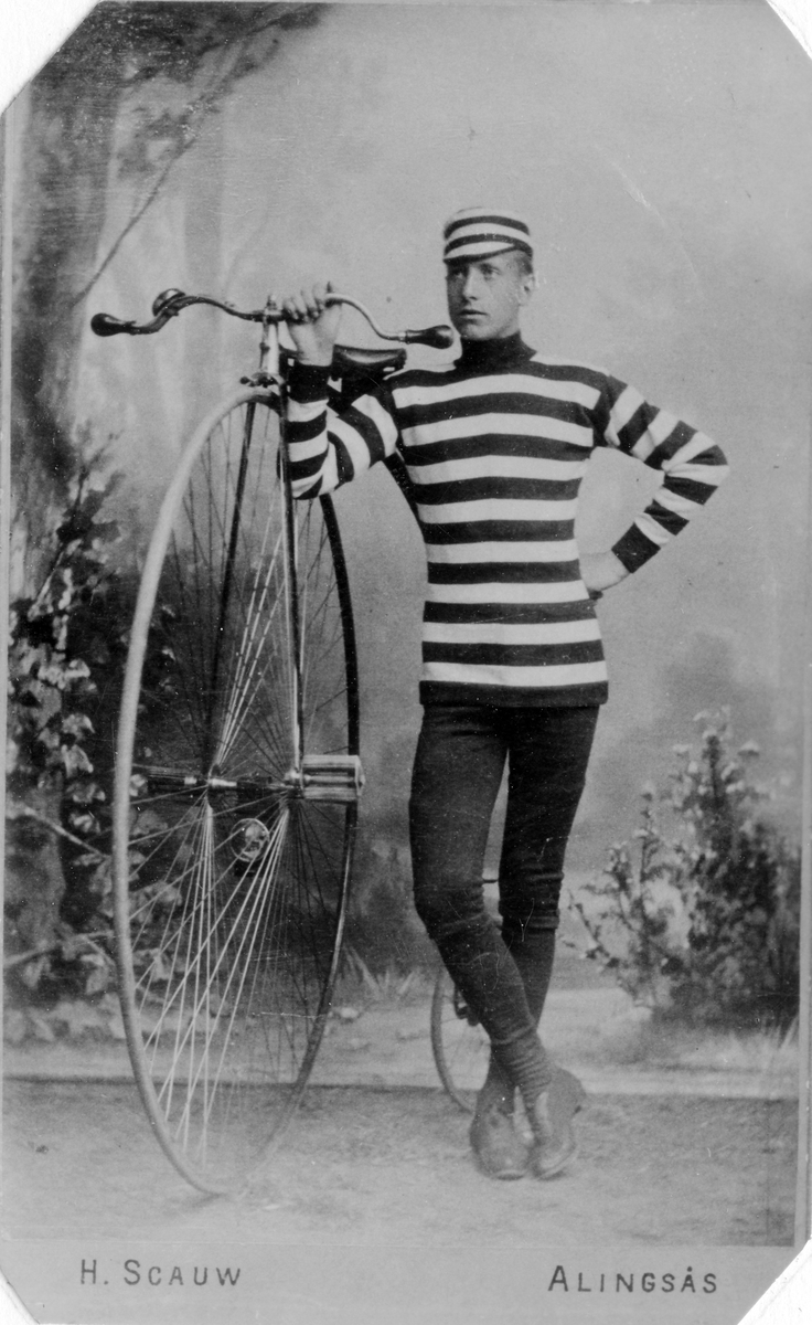 Herman Lindqvist står bredvid en cykel, en höghjuling, klädd i vit/svart-randig tröja och mössa, i en fotostudio. 
Lindqvist var född i Alingsås, affärsman i Göteborg.