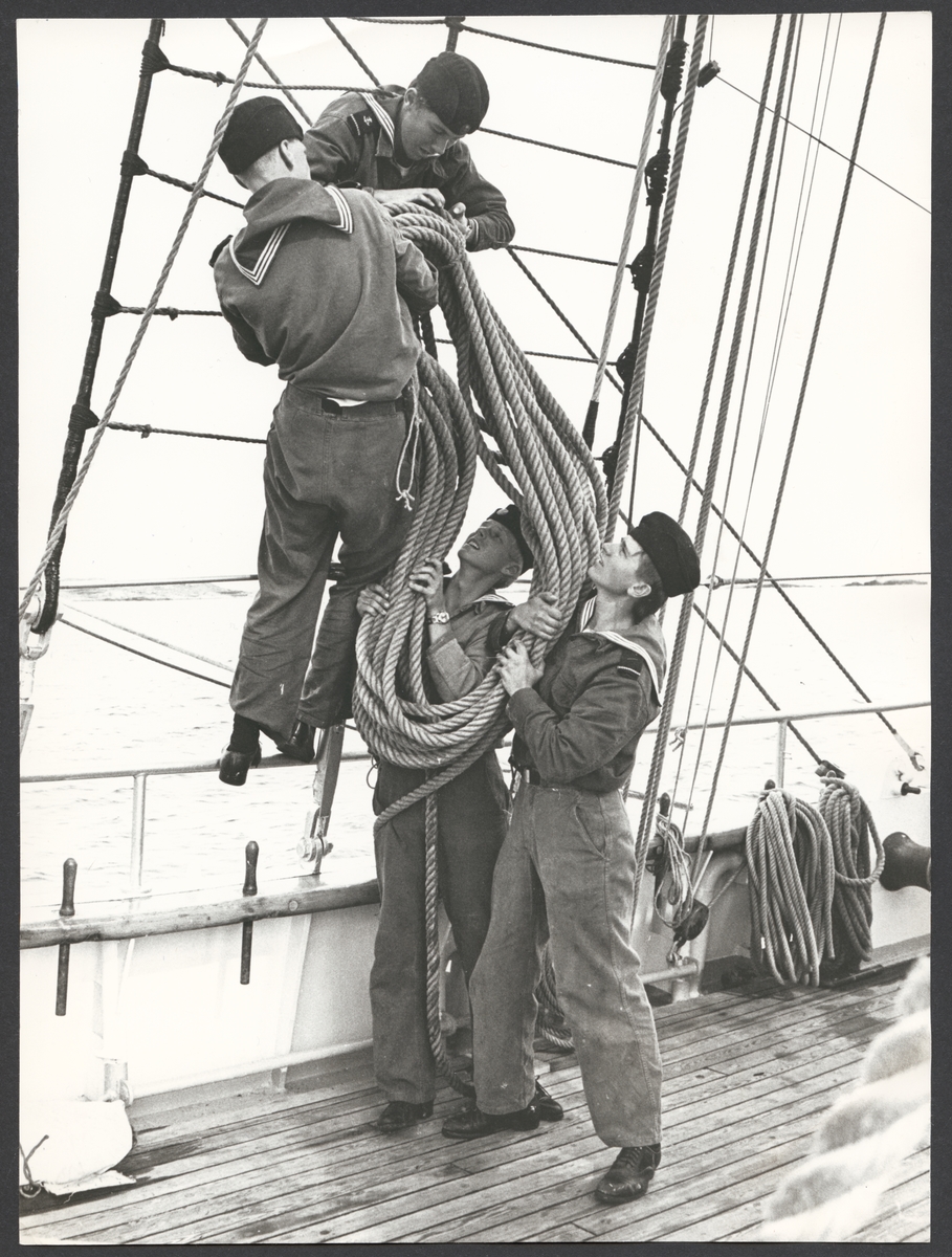 Bilden visar fyra kadetter som försöker lyfta en rep på en av flottans skolfartyg Gladan eller Falken.