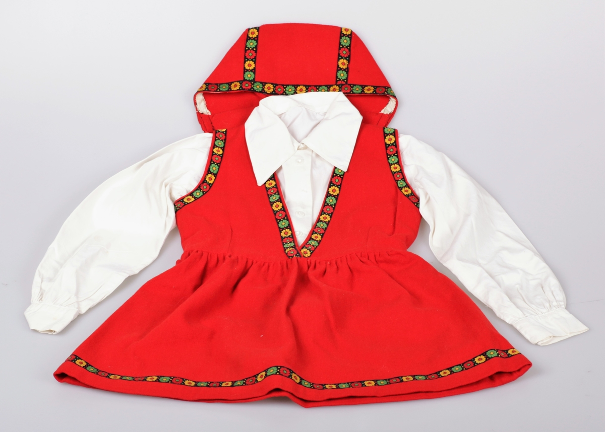 Festdrakt sydd av rød ullfilt. Den har et formsydd liv, og skjørtet har god vidde. På skjørtet og livet er det påsydd et dekorbånd. Drakta har samme stil som TM-15841. Det hører med en kyse til antrekket, og den er registrert som TM-15847. Tilhørende skjorte til kjolen er registert som TM-15845. Fire søstre hadde like ens hjemmessydde kjoler som dette.