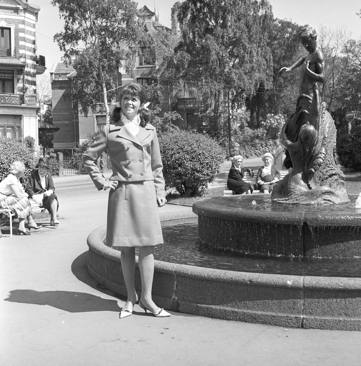 Wenche Myhre står ved en fontene. Fotografert 10.06.1965
.