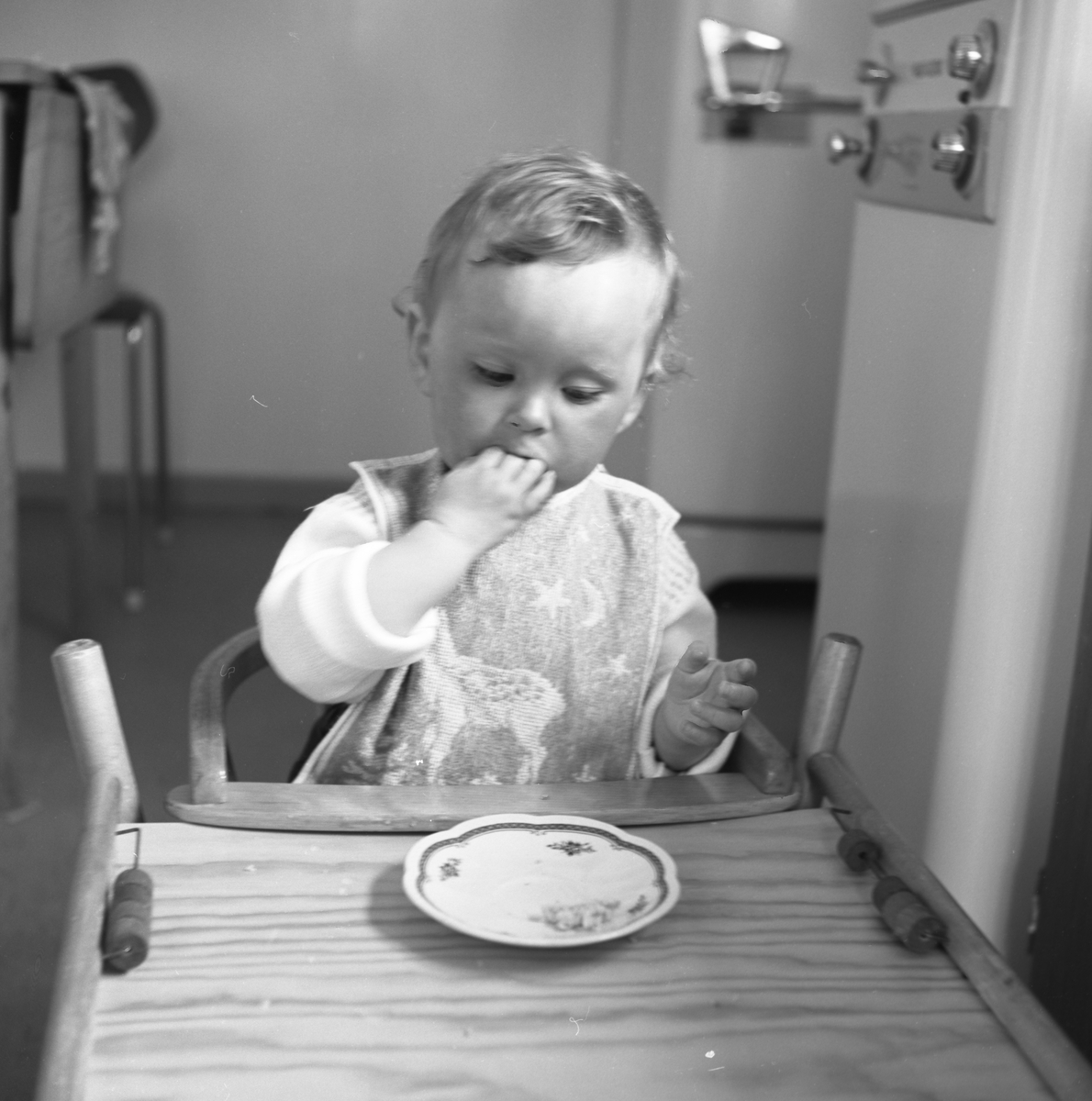 Portrettfotografi i serie av ei lita jente, Astri, som sitter i en barnestol og spiser kveldsmat.