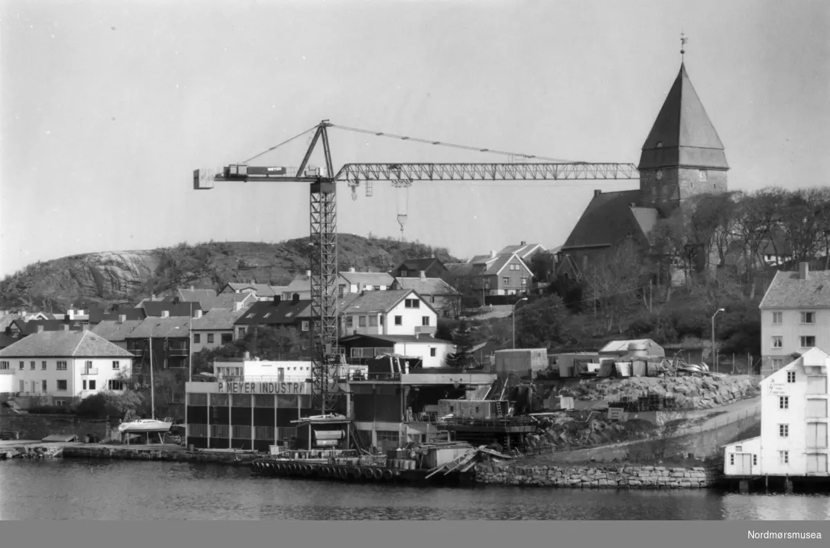 Foto fra Nordlandet i Kristiansund, med P. Meyer Industri ved sjøkanten og Nordlandet kirke lenger bak. Fotoarkivet stammer fra Nordmørsposten, og inngår nå i Nordmøre museums fotosamlinger.