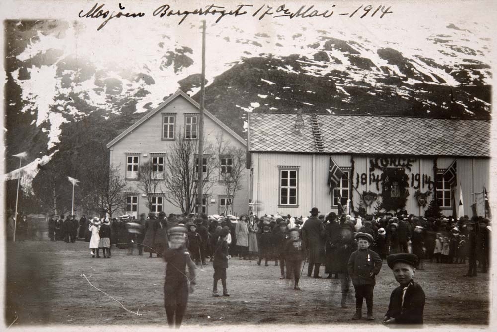 Postkort av Mosjøen Borgertoget 17. mai 1914. Norge 1814 - 1914 står på veggen med krans. Mange barn og folk.