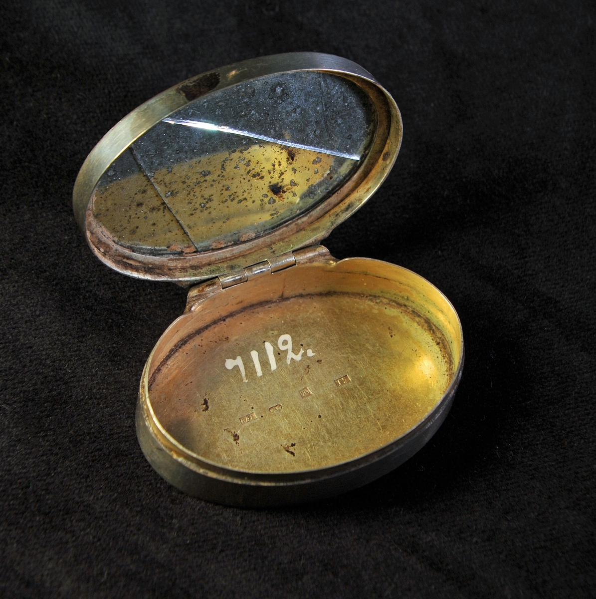 Oval dosa av silver. Graverad dekor i nyrokoko på locket. I botten ingraverade initialer: "J.C.J.S.". Invändigt förgylld med spegel i locket. Stämplad i insida i botten.