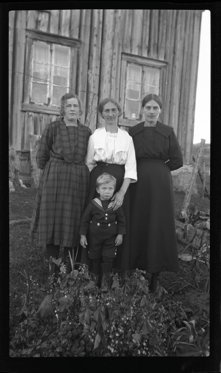 Gruppeportrett av tre kvinner og liten gutt på gårdstun.
