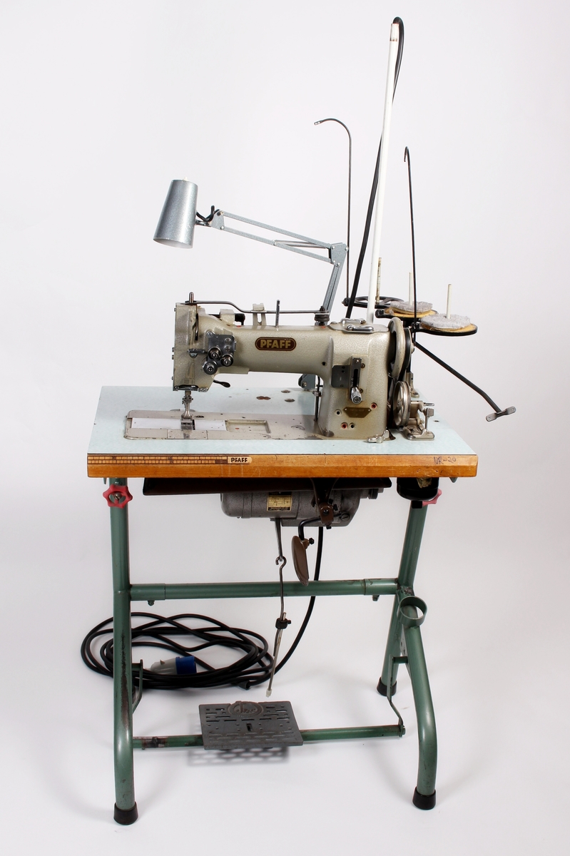 Symaskin med avtagbar sytrådholder til 3 spoler. Symaskinen er festet til et arbeidsbord og brukt hos Jonas Øglænd. Bruk: 1970-1979.
