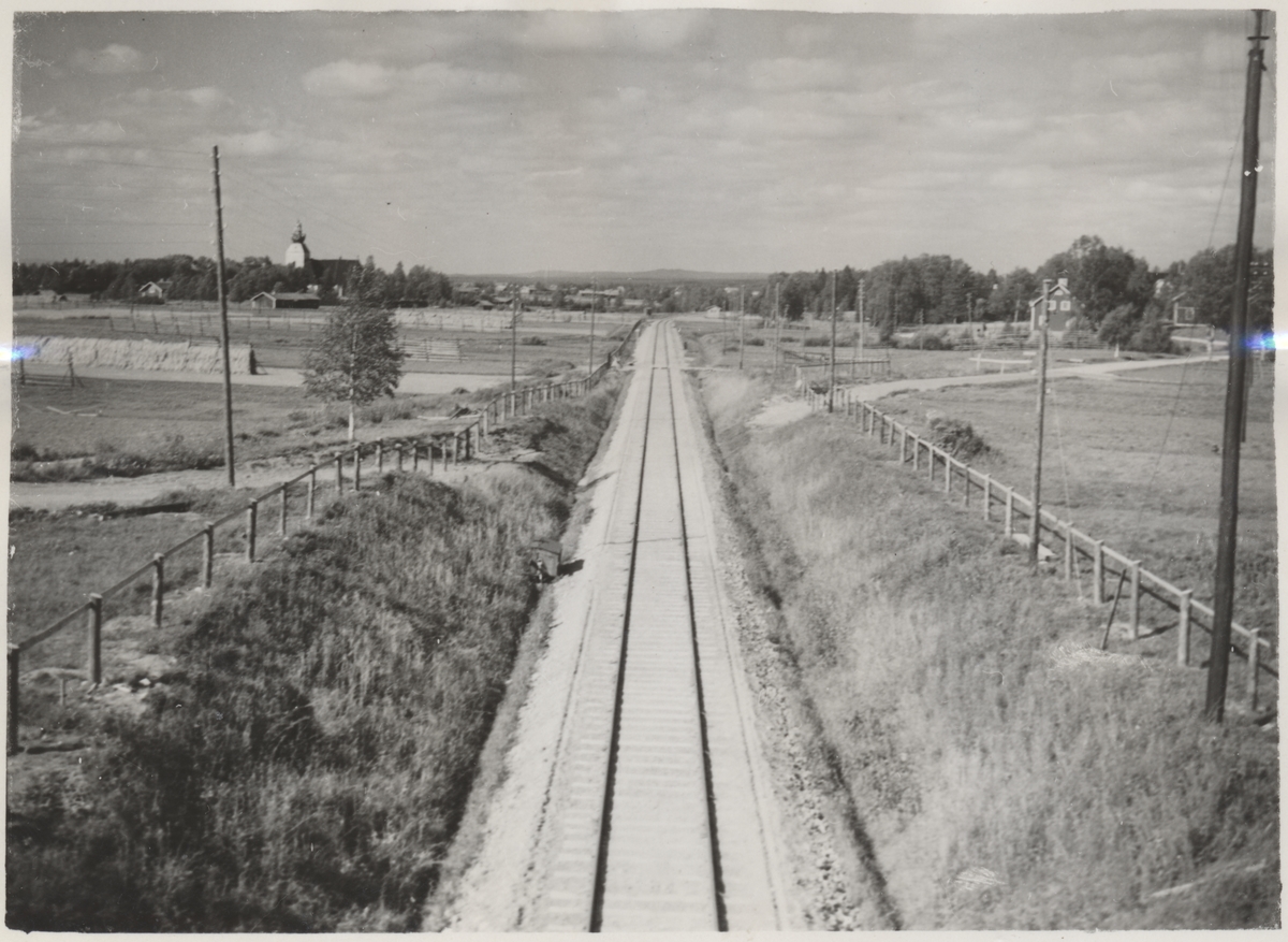 Bild tagen från vägbron i Grimsåker. I bakgrunden  till vänster ser vi Malungs Kyrka och längs järnvägsspåret vid kröken ligger Grimsåkers hållplats.