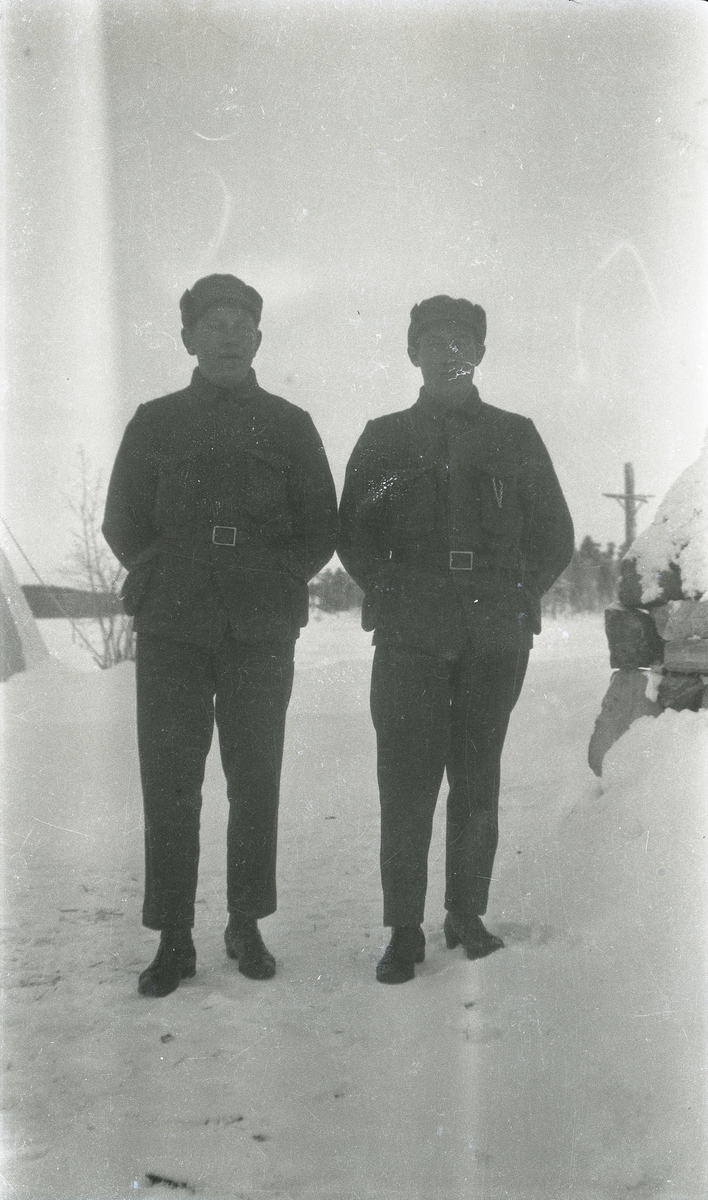 Portrett av to soldater stående utendørs.