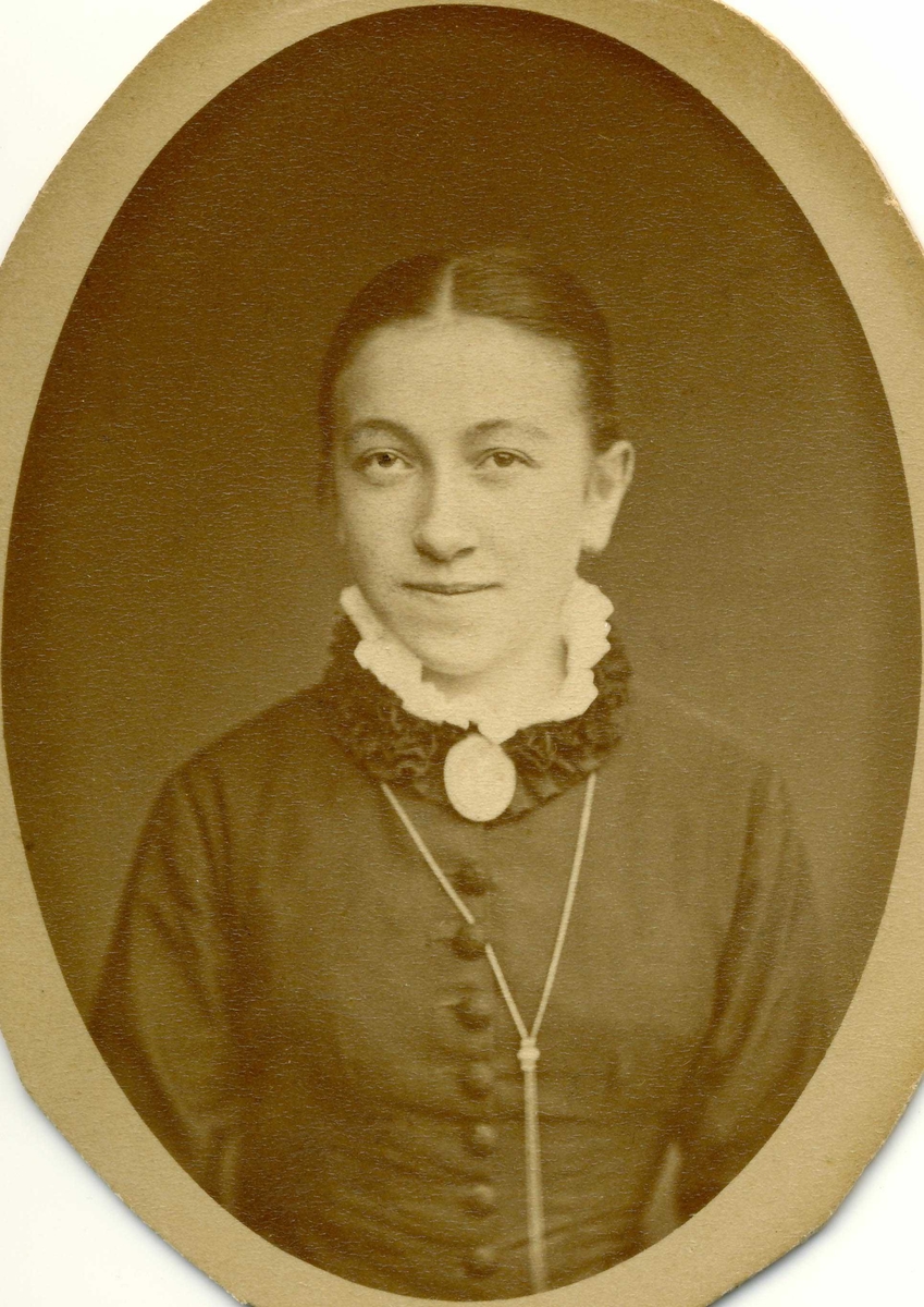 Portrett av Bergitte Esbensen i mørk kjole med medaljong. Ca 1880-årene