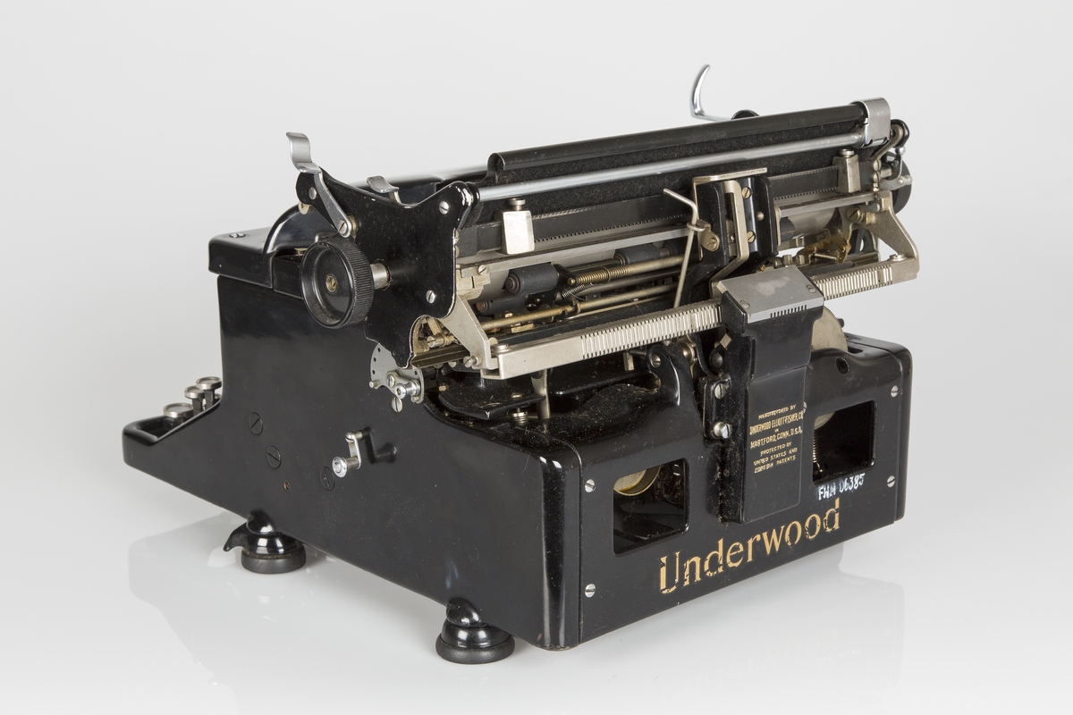 Rektangulær mekanisk Amerikansk-produsert skrivemaskin fra ca. 1900. Høy og tung modell. Står på fire gummierte føtter.