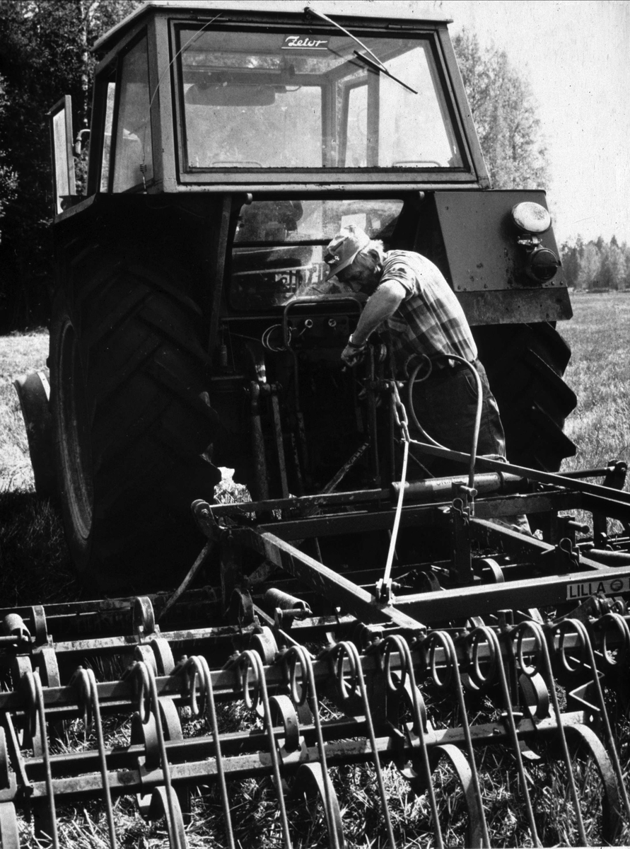 Lantbrukare Bertil Widblad kopplar på harven på traktorn, Mossbo, Tierps socken, Uppland maj 1981