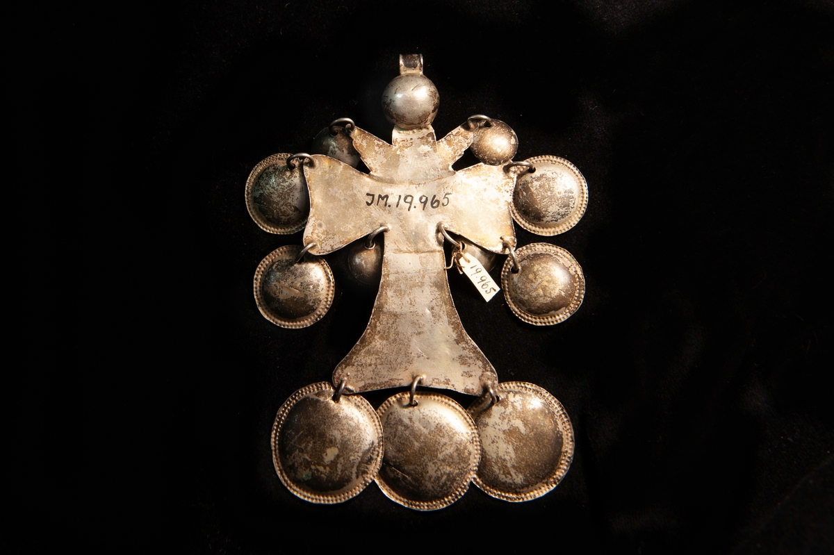Ett striglakors i ciselerat och förgyllt silver. Motiv i form av Jesus på korset med ett naivt änglahuvud ovanför. Behängt med 11 runda, små plattor ("skålar") av ciselerat och förgyllt silver. Delvis otydliga stämplar.