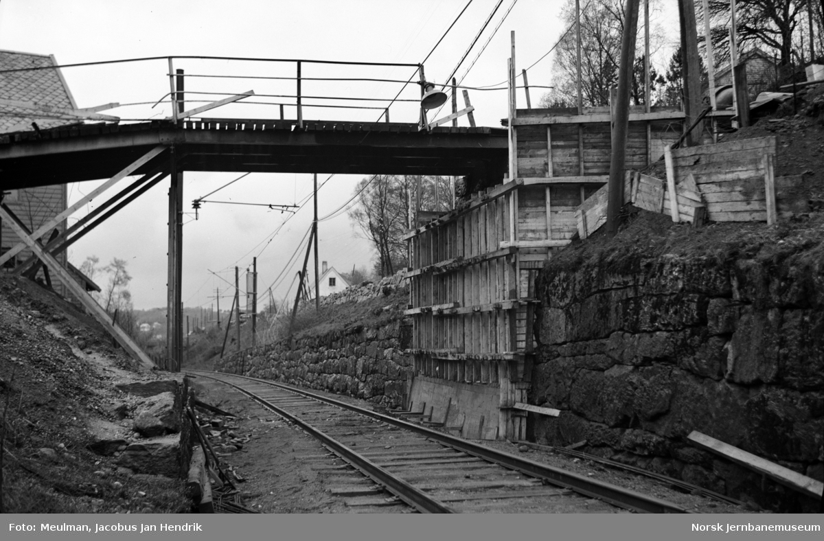 Arbeid med heving av overgangsbro i forbindelse med elektrifiseringen av Vossebanen. Forskaling av landkar. Her ved Jansen fabrikker ved Midttun, sett i retning Bergen.