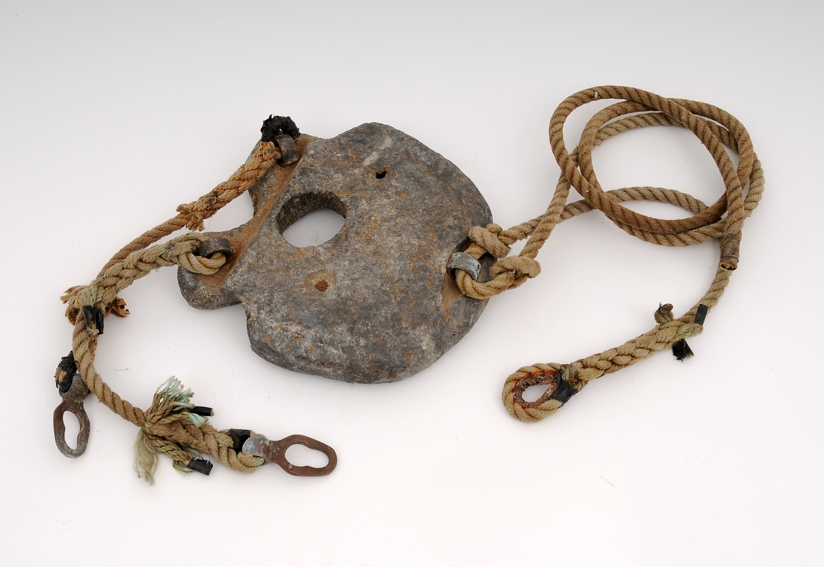 Sirkulært blylodd med med tre korte tau med bronsemaljer og spenner til å feste loddet til dykkerdrakten (TD.G-00342).