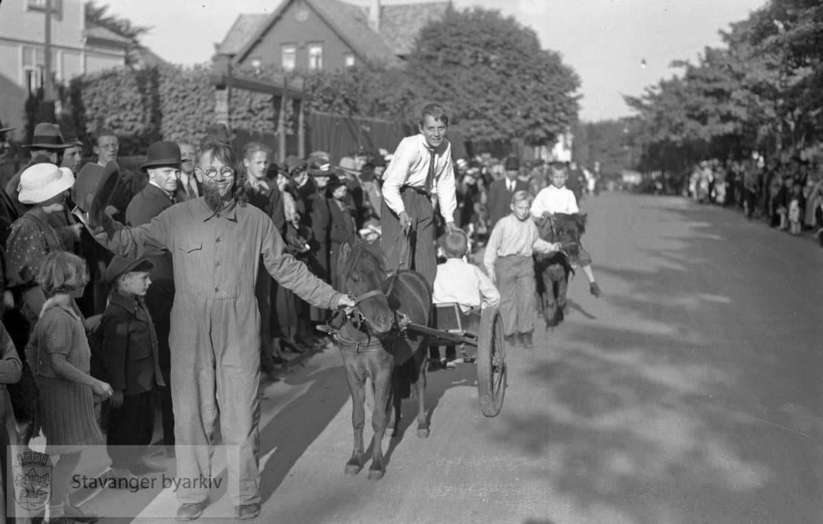 Lars H. Lende som funkismann leder an barn i kjerrer trukket av ponnier.