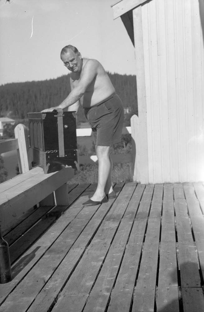 Arthur Skog står på balkong i shorts. Står med positiv (lirekasse).