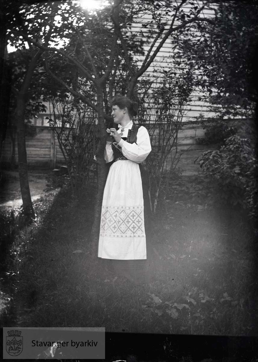 Kvinne, antakelig en Eckhoff poserer i hagen..Hardangerbunad, forkle med hardangerbroderi.