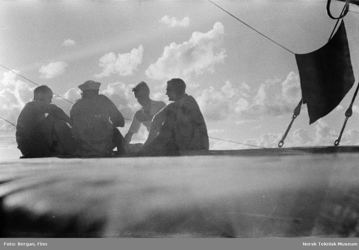 Sol og skyer, fire personer i motlys, på skipsdekk