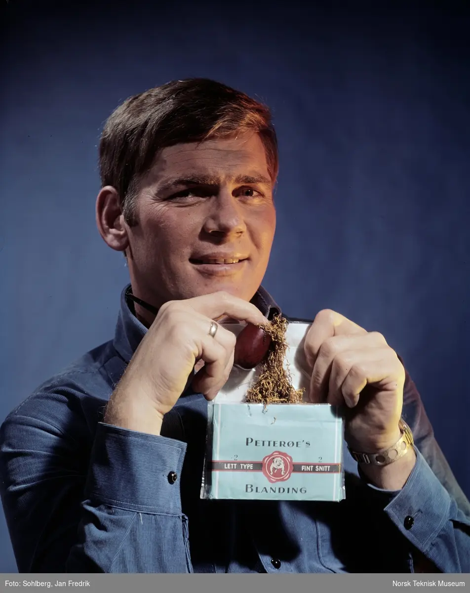 En mann ruller seg en røyk fra en tobakkspakke av merket Pettrøes blanding. Forbud mot å reklamere for tobakk og sigaretter kom i 1975.