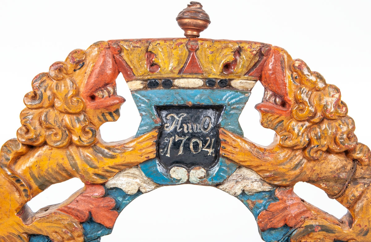Selbåge i trä, föreställande två lejon och kunglig krona.
Daterad enligt påskrivt "Anno 1704".