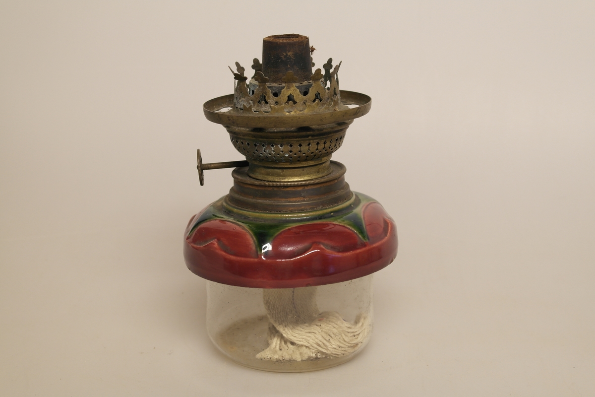 Parafinlampe i glass og malt keramikk, med lampeglassholder i messing. Det er veke igjen i lampen.