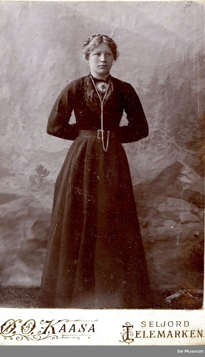 Atelierfoto av ei ukjent kvinne i mørk kjole.
