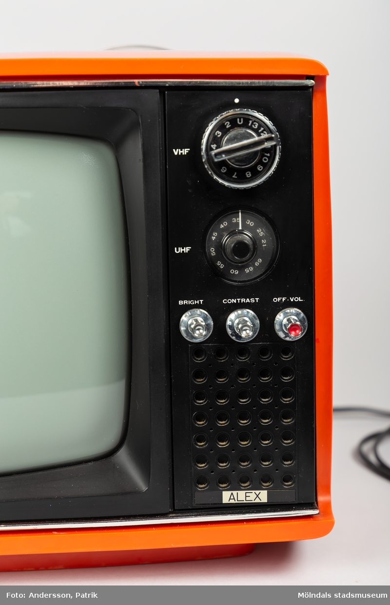 Liten röd bärbar tv med 11 tums skärm av märket ALEX. Tillverkad under 1970-talet.
Apparatens ytterhölje är av röd plast. Den har två större vred på vänster sida om skärmen, att välja tv-kanal med. Samt tre mindre vred att ställa in ljus, kontrast och volym med. På ovansidan finns ett utfällbart handtag att bära TV:n med.