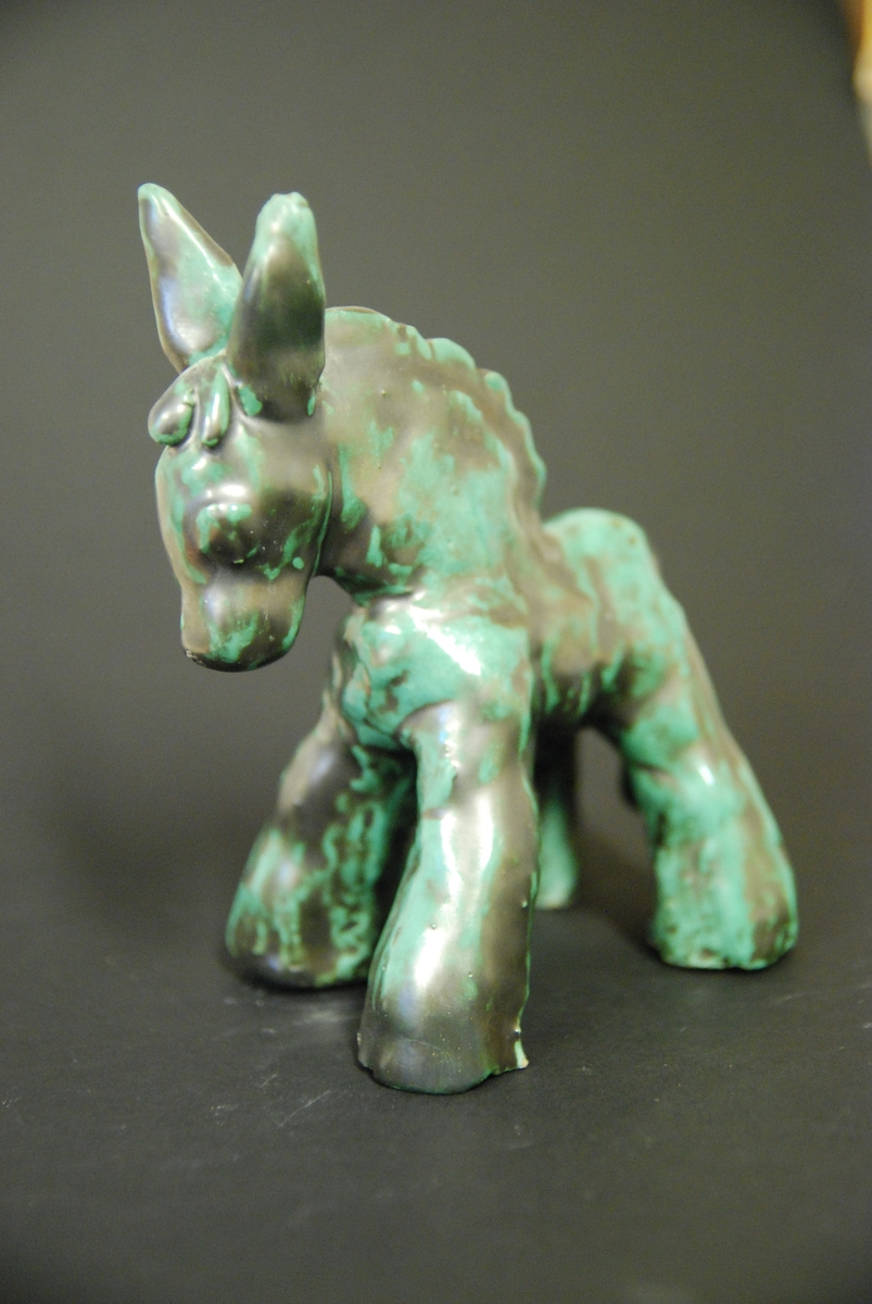 Figurin, mulåsna, lergods, grönsvart glasyr, formgiven av Märta Willborg, 1930-talet.
