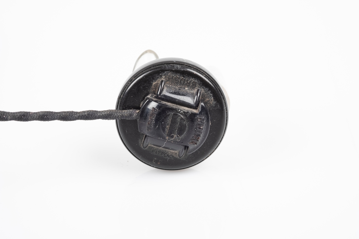 Ørepropper som kobles til radioen. Den har svart flettet ledning og propp i plast som kan fjernes fra ledningen. Den ene proppen mangler.