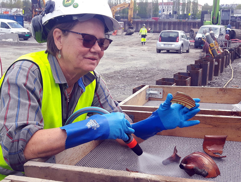 Arkeolog og funnansvarlig Susanne Pettersson i såldet -  med et tidstypisk skår i vårt undersøkelsesområde av havna; keramikk produsert i Weser-distriktet i Tyskland på sent 1500-tall. (Foto: NMM)
