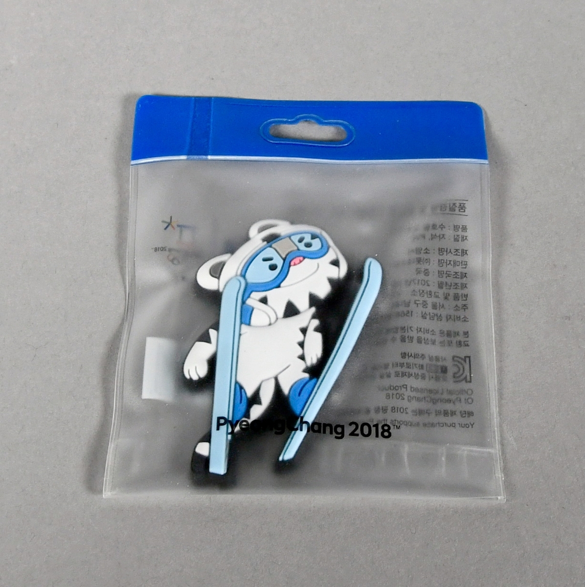 Figur laget av plast som viser maskoten Soohorang som hopper på ski og er utstyrt med skibriller. Figuren ligger i en plastemballasje. På baksiden er figuren stemplet med PyeongChangs logo og de olympiske ringene.