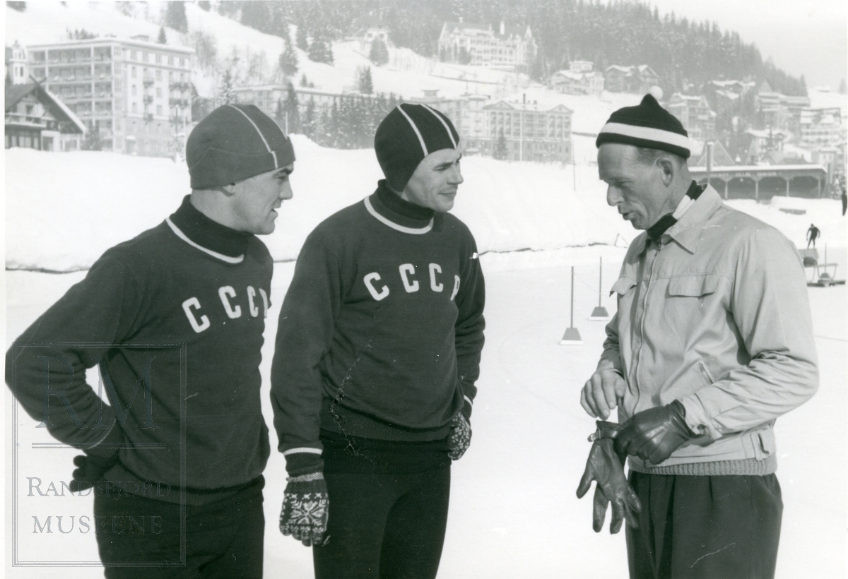 Hans Engnestangen stående sammen med to russiske skøyteløpere på banen i Davos.
