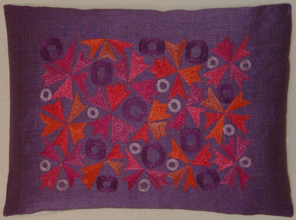 Kudde, violett halvlinneväv, broderier i lingarn med kedjesöm, stiliserat mönster.
