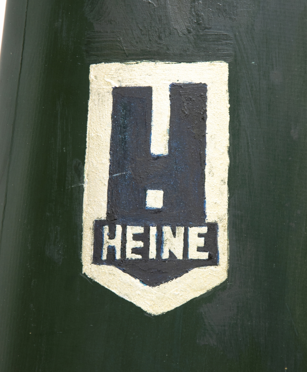Grön tvåbladig propeller av märket Heine. På vardera vingblad är tillverkarens emblem målat, ett svart H med silvrig bakgrund.