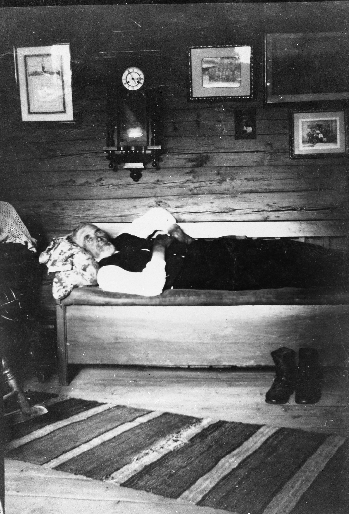 Eivind Tjensvoll ligg på benken i den gamle stova på Tjensvoll.