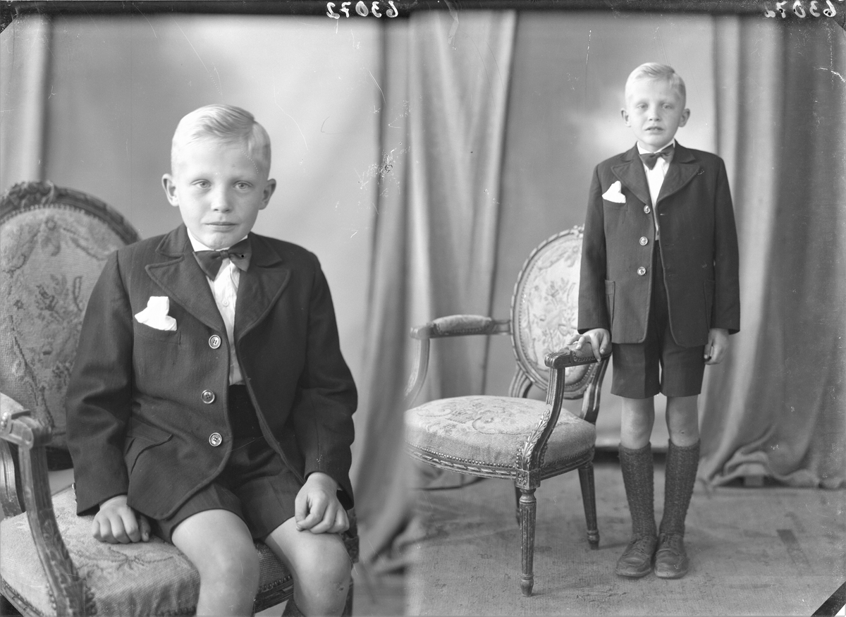 Portrett. Ung lyshåret gutt i mørk dress, kortbukser, hvit skjorte og mørk sløyfe poserer sammen med en brodert stol. Bestillt av Liken Hansen. Salhusveien.