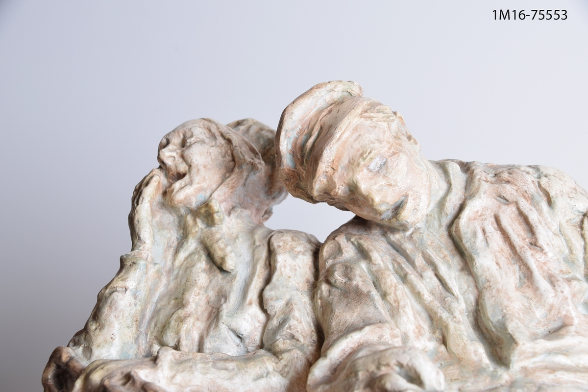 Skulptur i patinerad gips, med titeln "Afton" som visar en trött och gäspande kvinna som sitter tillsammans med en sovande man. Skulpturen är en variant på genreskulpturen "Omnibusseen" från 1906.
