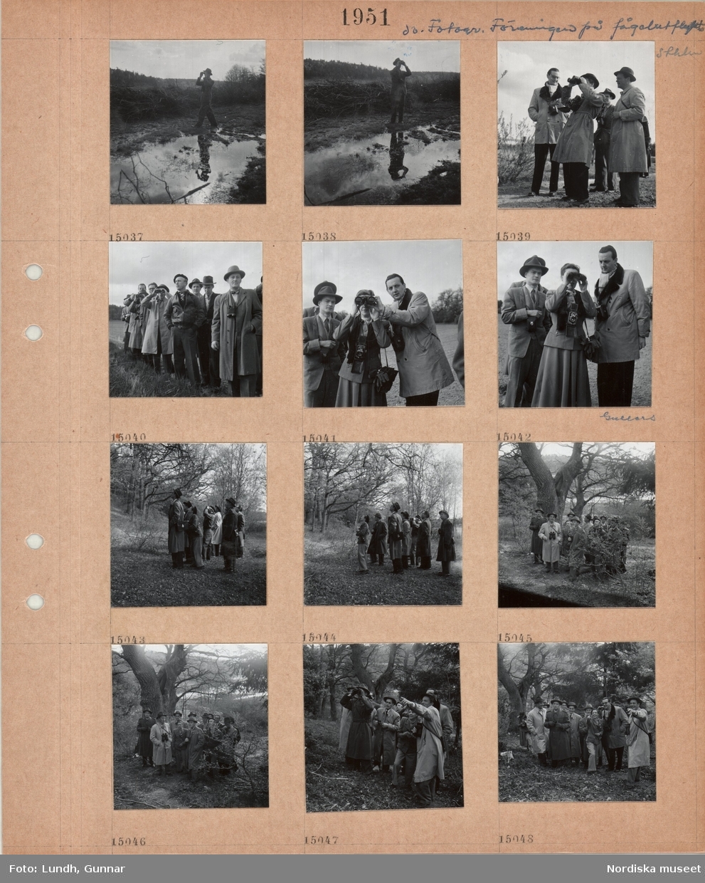 Motiv: Fotografiska Föreningens fågelutflykt Sthlm (Stocholm) ;
En man tittar i en kikare, en grupp män varav en är fotograf K W Gullers och en kvinna tittar i kikare, en grupp män och en kvinna står i en skog.
