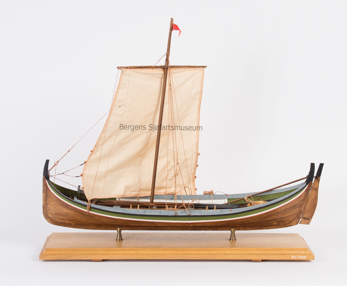 Helmodell av nordlandsbåt, seksæring. Modellen er rigget med råseil, har tiljer, årer, stamp og anker.