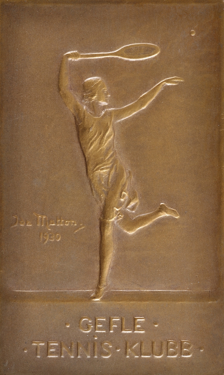Idrottsplakett, brons, utförd av Ida Matton 1930.
Text "Gefle tennisklubb".
Bild av tennisspelande kvinna.