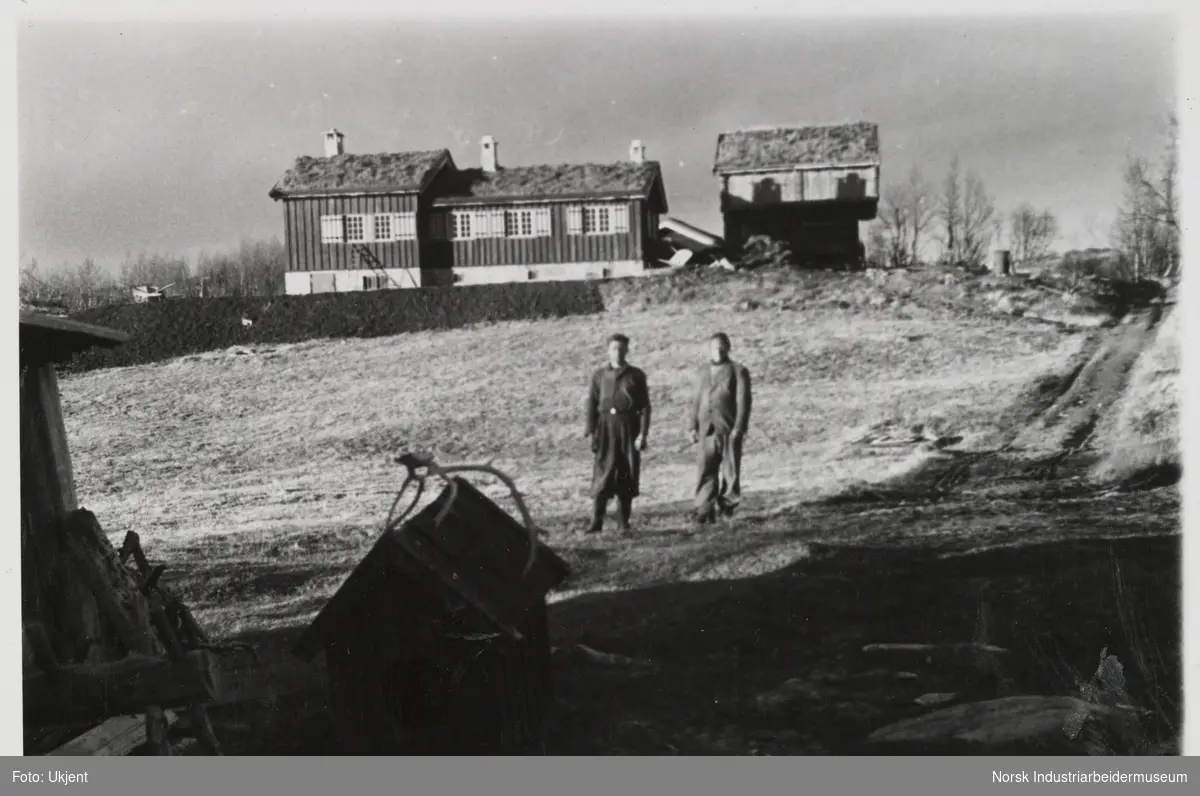 To menn foran bygninger på Sundet, Møsstrond. I forkant et hundehus med gevir på taket