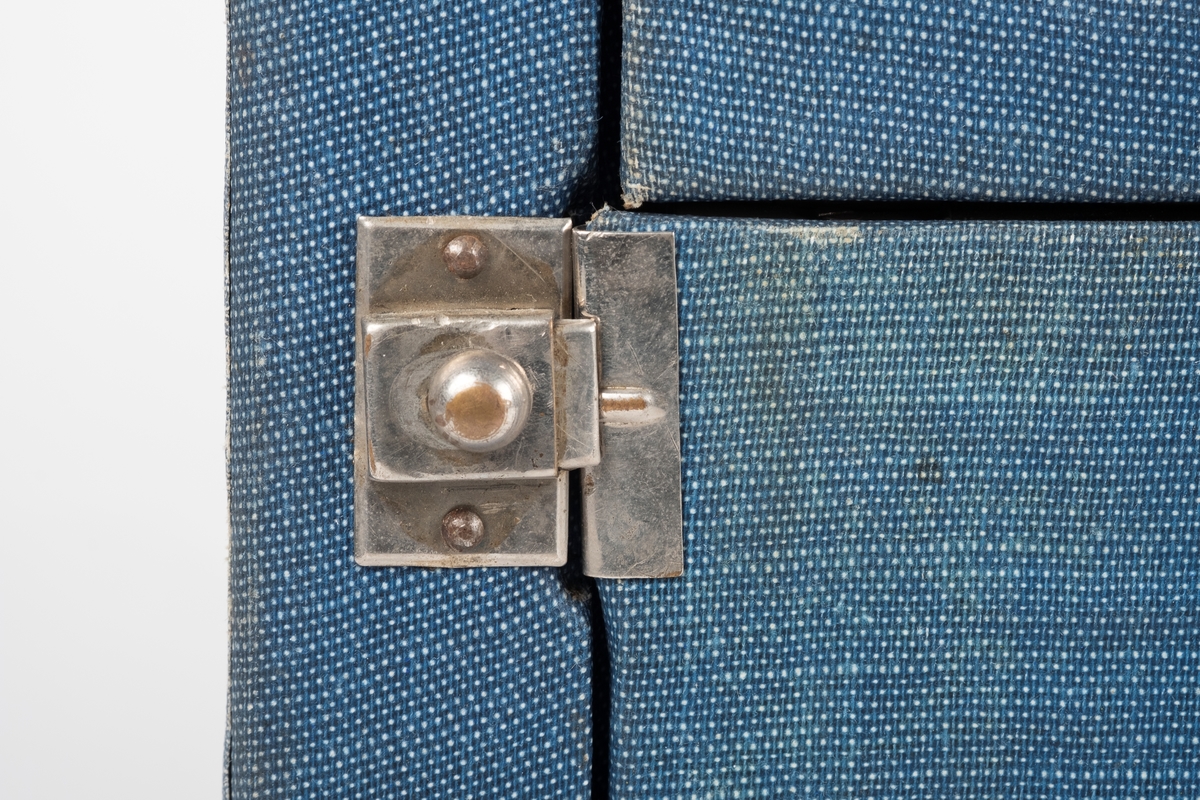 En radio kledd med blått tekstil. Radioen har lokk i front og kan bæres med håndtak. Lokket kan brettes sammen i to. Bak lokket er høyttaleren, kanaloversikt og 4 svarte vridere. På baksiden er det 4 hull og tilkobling av ledninger.