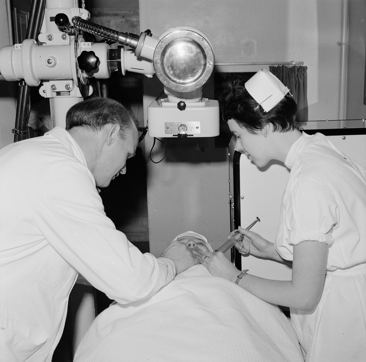 Läkaren Olof Olofsson och sjuksköterskan Karin Anens förbereder en röntgenundersökning av en hjärnpatient, Akademiska sjukhuset