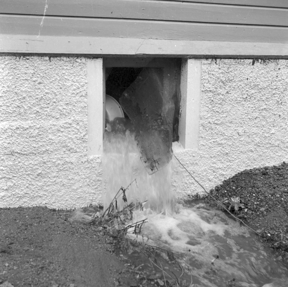 Vatnet fløymer ut eit kjellarvindauga etter flaumen i 1962