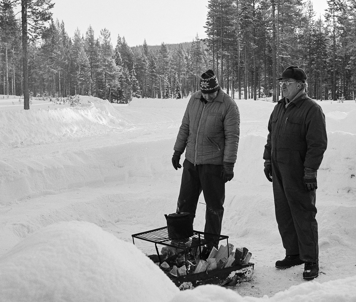 Sveg 1984.
Motortekniker Roland Svensson och tekniklärare Bengt Lundblad väntar på en kurs "någonstans i skogen" för att genomföra ett vårdpass. Elden var den naturliga samlingspunkten för alla.