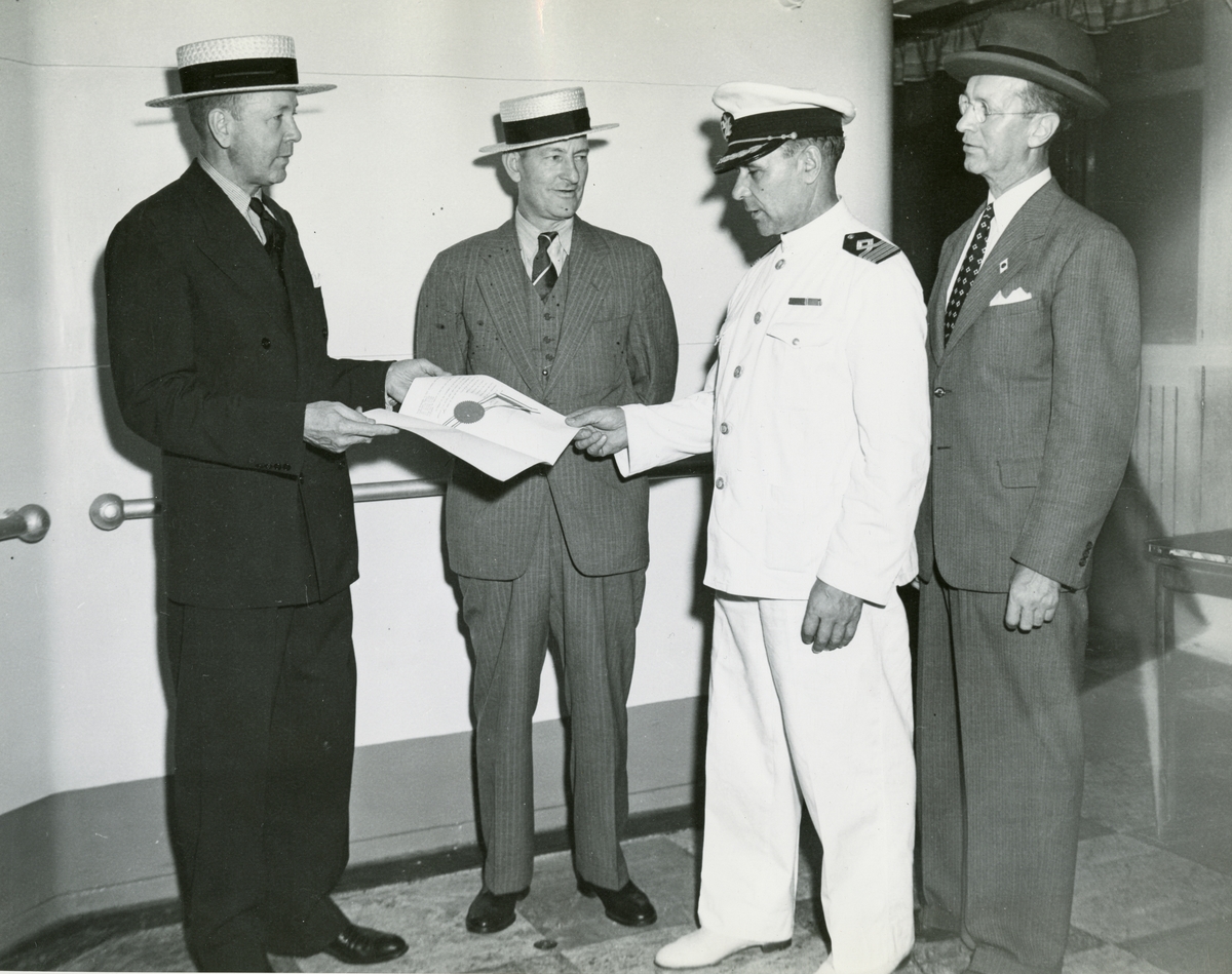 Sigfrid Ericson fotograferas av den amerikanska pressen ombord på Gripsholm när han tar emot dokumentet om fri lejd av amerikanska statstjänstemän. Dokumentet användes i samband med fångutväxling mellan USA och Japan.