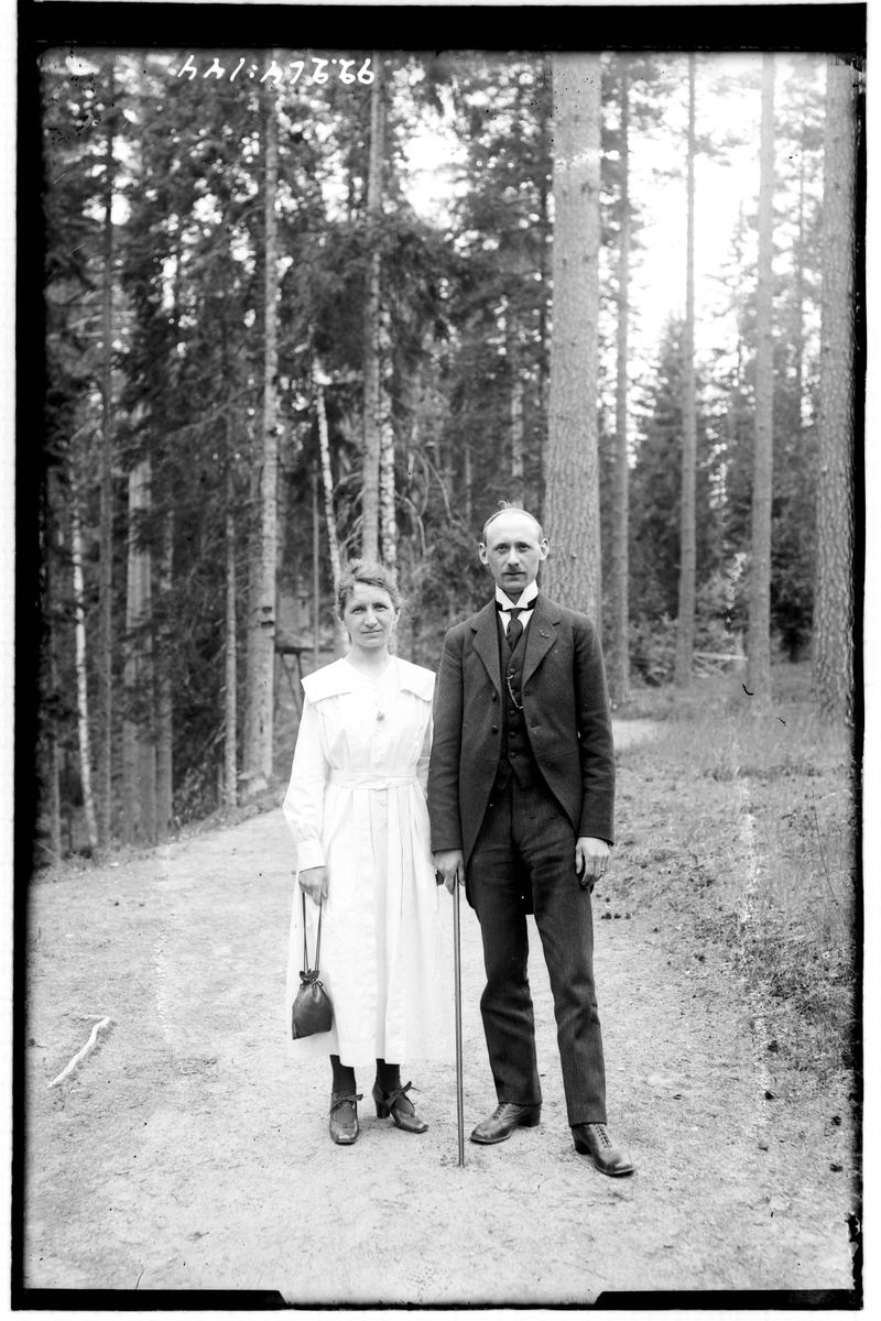 Hålahult sanatorium, exteriö, en man och kvinna på en stig i skogen, uppklädda.