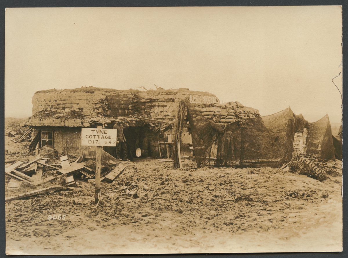 Bilden visar resterna av en bunkeranläggning i armerad betong som var kamouflerad. Vid ingången bakom skylten "Tyne cottage" står en ensam soldat.